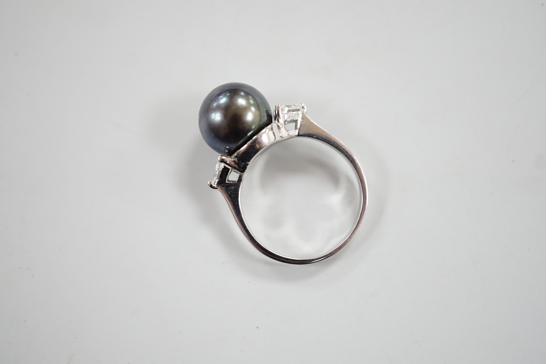 A modern 750 white metal, single stone Tahitian pearl and two stone trillion cut diamond set ring, size O, gross weight 5.6 grams.